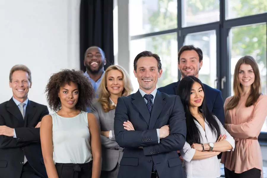 Professional photo of eight well-dressed IT team members in an office setting.